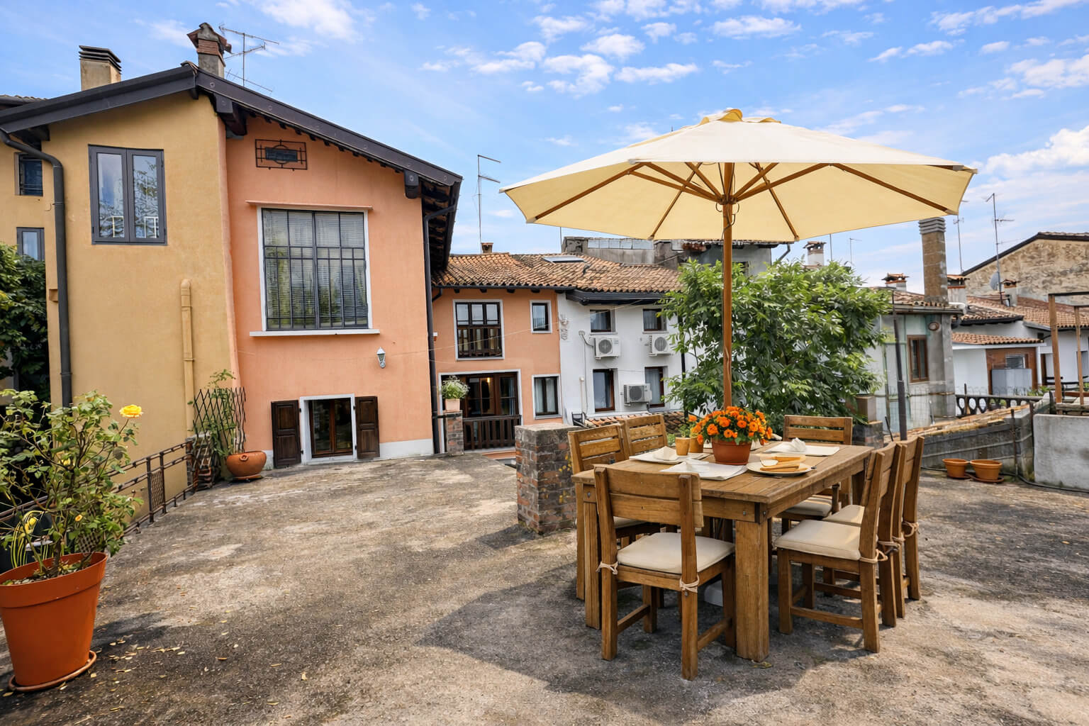 Haus mit großer Terrasse und gedeckten rustikalen Tisch mit Sonnenschirm