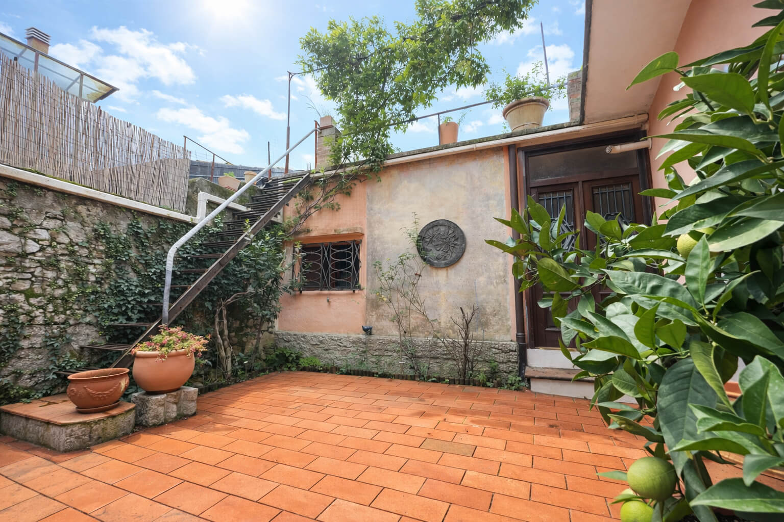 Alter Hinterhof mit Terracotta Fliesen und Stiegenaufgang auf die Terrasse