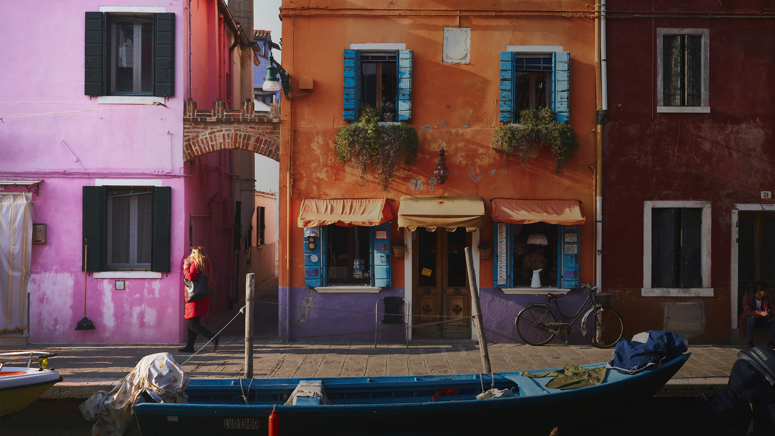 Bunte Häuserfassaden mit blauem Boot im Vordergrund in einer italienischen Gasse.