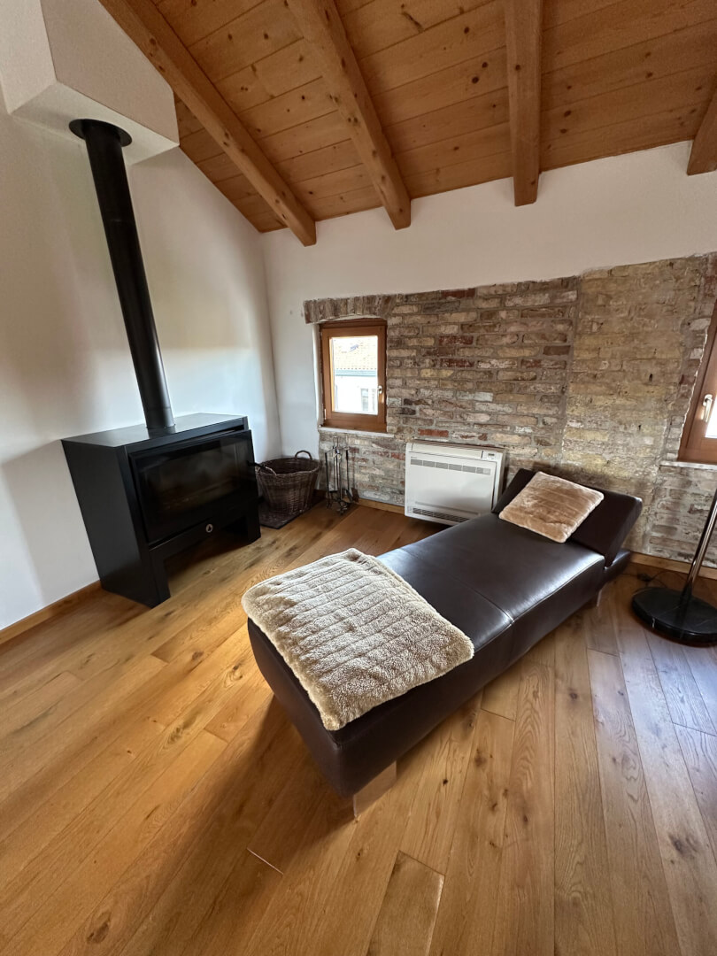 Dachgeschoss mit sichtbaren Natursteinwänden und dem Holzkamin