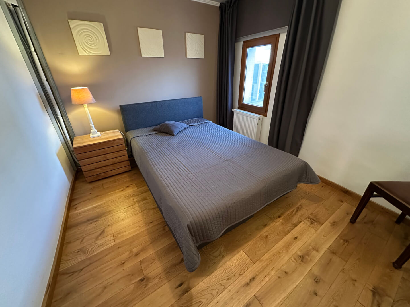 Schlafzimmer mit Ansicht des Ehebettes mit wunderschönem Holzfußboden und warmer Atmosphäre